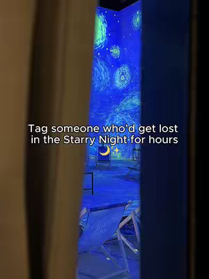 The image shows a view through a vertical opening in a frame, possibly curtains or a doorway. Inside, a room is illuminated with a projection of Van Gogh's 'Starry Night' painting dominating the entire wall. Two beach chairs are positioned within the projected scene, suggesting an immersive environmental setup. The overall composition frames the scene theatrically.