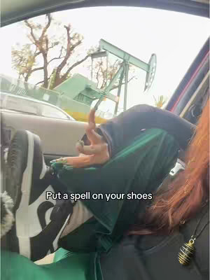 The cover image shows the interior of a car. The legs of a person are visible, with the shoes prominently displayed. The person is wearing a green outfit. Outside the car window, an oil pump jack is visible, suggesting a natural backdrop. Text overlayed on image.