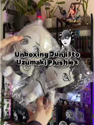 The cover photo features an unboxing scene. The creator's hands hold two plushies of characters from Junji Ito's manga Uzumaki. The plushies are in plastic packaging. The background shows shelves with items, including plants and figures, suggesting the creator's personal space.