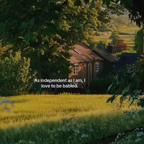 A peaceful landscape shot featuring a small house nestled among trees and a field of wheat. The warm, inviting color palette includes greens and browns. The text overlay adds a personal touch.