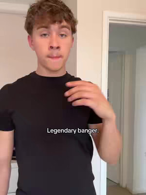 A young man in a black t-shirt is shown from the chest up, standing in front of a plain wall and a partially visible doorway. The text overlay reads 'Legendary banger.'