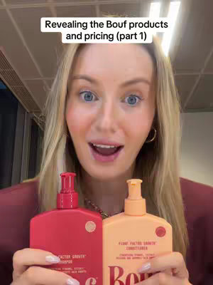 The cover image is a selfie-style shot featuring a woman holding two bottles of haircare products. She is positioned in the center with the products in front of her. The woman is looking directly at the camera with a surprised or excited expression, her mouth open. She has long, blonde hair and is wearing a burgundy-colored top. Above her head, the text overlay reads, "Revealing the Bouf products and pricing (part 1)". The background gives a glimpse of what appears to be an interior space, dimly lit. The overall composition focuses on the creator and her product display.