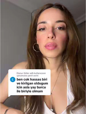 A selfie-style shot featuring a woman with long brown hair, posing in front of a nondescript background. She has fair skin, wears minimal makeup, and is dressed in a white top. A comment bubble overlay appears on the lower left, with Turkish text in a simple sans-serif font, which is partially obscuring her body. The expression on her face hints at an open attitude.