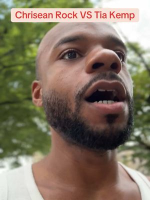 A close-up shot of a Black man with a shaved head and full beard, looking up with an open mouth. Text overlayed at the top reads : Chrisean Rock VS Tia Kemp. The background is blurred green foliage, suggesting an outdoor setting.