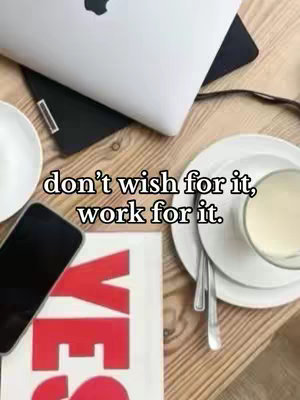 A top-down shot of a wooden table with a laptop, a smartphone, a book with the word 'YES' in red, utensils, a saucer, and a cup with a milky liquid. The overlay text that states the hook of the video is located at the top center of the image.