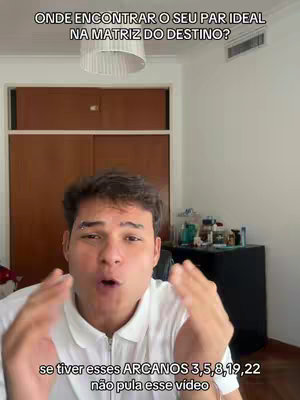A man with surprised expression is gesturing with hands up and out, in front of a simple background.