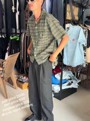 A man wearing sunglasses stands in front of clothing racks, the image showing his outfit and some price information.