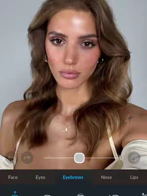 A close-up shot of a woman with long brown hair, wearing makeup and a necklace. The image appears to be a screenshot of a photo editing app, with options like 'Face', 'Eyes', 'Eyebrows', 'Nose', and 'Lips' visible at the bottom.