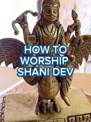 The cover image shows a golden statue of a deity with large wings, holding weapons. Overlayed text reads, "HOW TO WORSHIP SHANI DEV."