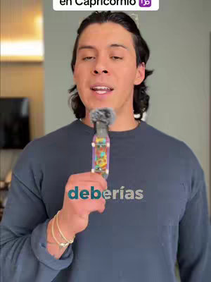 A man, with dark hair, is holding a microphone. The background is somewhat blurred but appears to be an indoor setting. In the image, the text overlay says "deberías". The man is looking directly at the camera.