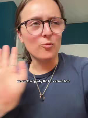A woman with glasses looks up while speaking, with text overlayed and her hand up in the air.