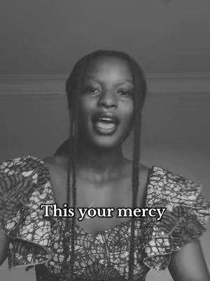 A black and white photo featuring a young woman with dark skin, facing forward with an open mouth. She has long braids, and she's wearing a top with a floral pattern. The text overlay 'This your mercy' is visible beneath her.