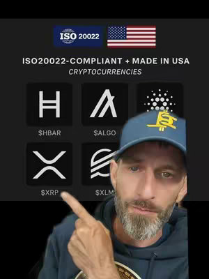 A selfie-style video cover image features a man pointing at a display of cryptocurrency logos against a dark background. Above the logos are the ISO 20022 logo and the American flag. The man is wearing a blue cap with a logo and a navy blue hoodie.