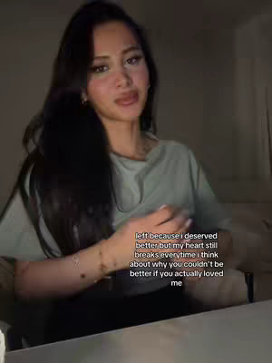 A woman with long dark hair is centered in the frame, slightly angled to the left. She wears a light green top and is looking slightly off-camera. Text overlayed on the bottom right provides additional context.
