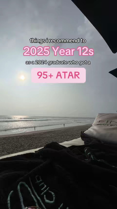 The image captures a serene beach scene with a vast sky. A pink rectangular overlay with white text floats in the upper portion of the image, and in the foreground, a dark folded blanket suggests relaxation.