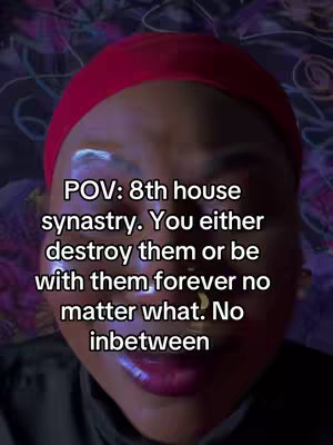A close-up selfie showing a person with dark features, wearing a red headwrap. The person's face is centered, with a close focus on their eyes and lips. Overlayed on the image is white text discussing astrology.