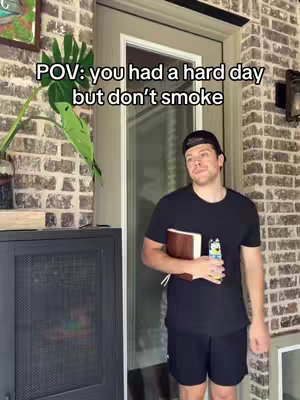 The cover image shows a man standing by a brick wall and a glass door. Text overlay reads, 'POV: you had a hard day but don't smoke.' The man is wearing a baseball cap, dark t-shirt, and shorts, holding a book and a small bottle. He appears to be looking at the camera with a thoughtful expression.