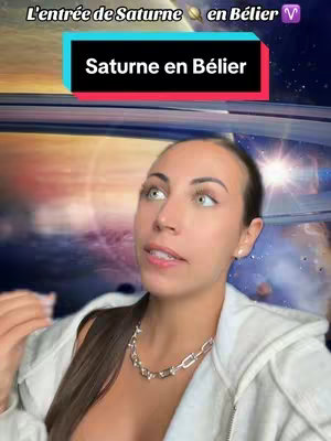 The cover image is a selfie-style shot featuring a woman against a backdrop of space-like imagery. Text overlays appear at the top, indicating the content's focus on Saturn's entry into Aries. The woman is in the foreground, wearing a white top and a silver necklace. She is looking toward the camera, and is speaking. The background shows swirling cosmic structures with a light source providing a warm glow.