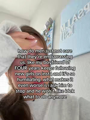 A selfie-style video cover image featuring a young woman with her hand covering her face, partially obscuring her features. Text overlays are present, conveying a message related to relationship issues. The background is somewhat blurred, with a pale blue sign visible on the right of the frame.