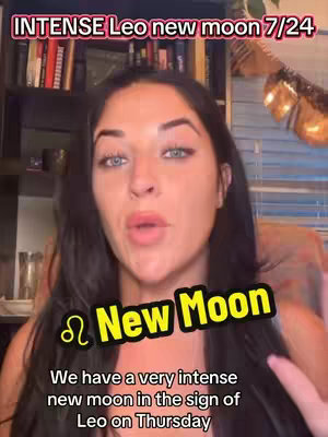 A woman with dark hair and fair skin looks directly at the camera. A text overlay in a bold yellow font with a black outline reads "New Moon" with a Leo symbol beside it. The background includes various visual elements: a bookshelf with books, a decorative object of golden feathers, and a glimpse of blinds.