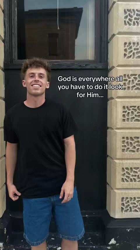 A young man is smiling and standing in front of a dark, textured doorway. Text appears to the right of the man, stating 'God is everywhere all you have to do it look for Him.'