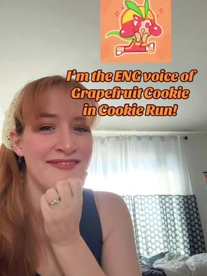 A woman with red hair smiles, hand under her chin. She wears a blue tank top, and a white lace hair accessory. Overlayed above her is a cartoon image of Grapefruit Cookie. Text in the cover image reads "I'm the ENG voice of Grapefruit Cookie in Cookie Run!"