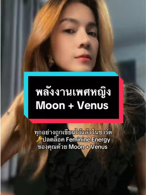 A woman with long auburn hair is centered in a selfie-style shot. She's wearing a black top and pinkish-red lipstick, looking towards the camera. A graphic overlay reads "พลังงานเพศหญิง Moon + Venus" in white text with a black and turquoise background. Beneath this, smaller text states "ทุกอย่างถูกเขียนไว้แล้วในชาร์ต ปลดล็อค Feminine Energy ของคุณด้วย Moon + Venus". The background appears blurred, suggesting an indoor setting.