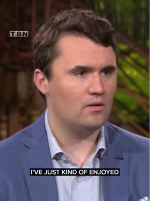 A medium shot of a man in a blue suit, centered on his face. Text appears in a black box at the bottom of the screen. The background is out of focus, suggesting an interior setting, possibly a television studio. The man appears to be in the middle of speaking. The TBN logo is visible in the top corner.