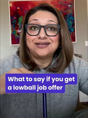 A woman with a warm smile and glasses is centered in the frame, set against a backdrop of an abstract painting. A purple rectangle with white text lies over the bottom portion. She wears a gray jacket, and her short, brown hair frames her face. The lighting is soft, emphasizing her facial features and the text overlay.