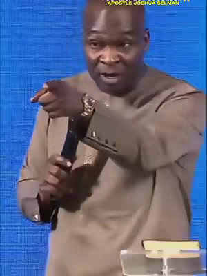 The cover image features a man speaking into a microphone, pointing with his right index finger. He is wearing a brown long-sleeve shirt. The background is a blue, textured wall, and the top of the image features text containing the name \"Apostle Joshua Selman\". A portion of a book rests on a stand in the foreground.