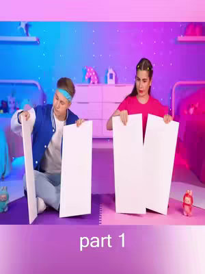 The cover image shows two people in a bedroom setting, each holding large white pieces of paper. The person on the left is a male wearing a blue jacket and headband, while the person on the right is a female wearing a pink shirt. The background features beds, a dresser, and a wall lit with pink and blue neon lighting. On the bottom of the image is textual information overlaid onto it.