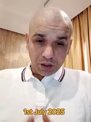 A man with a shaved head is centered in the frame, wearing a white polo shirt with blue and red stripes around the collar. The background includes a textured, light-colored wall and a darker, possibly wooden, wall on the right. The text overlay at the bottom of the picture says "1st July 2025".