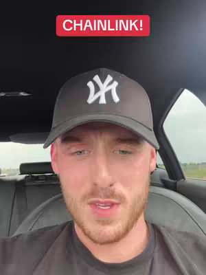 A selfie-style video cover image featuring a young man in a car. The man is wearing a black cap with a white logo and looking directly at the camera. A graphic overlay reads "CHAINLINK!" in red. The background is the interior of the car, with a road visible through the window, suggesting a driving scene.