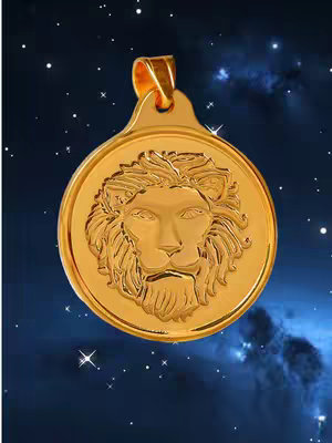 A close-up product shot featuring a gold pendant with a lion's head design. The pendant is centrally placed against a dark blue background speckled with what appears to be stars and nebulous cloud-like formations. The lion's head has intricate detailing, and the pendant has a loop at the top for hanging. The overall composition is well-lit, with a focus on the shiny gold material.