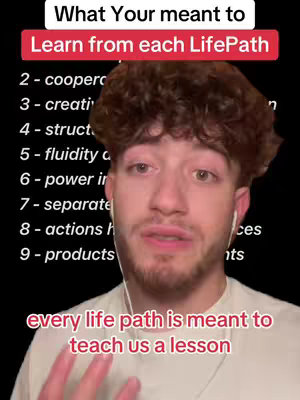 A selfie-style video featuring a young man in front of a black background. He has short curly dark hair and a neutral expression. The overlay includes text about life paths and their lessons. A white text box at the top says, "What You're meant to Learn from each LifePath" followed by numbers and words describing different life paths' meanings, and at the bottom "every life path is meant to teach us a lesson".
