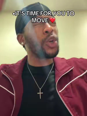 A man wearing a black durag and a red jacket with a silver cross necklace speaks directly to the camera, with text overlayed at the top of the screen.