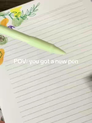 The image shows a close-up view of a notebook with lined paper. A light green pen is positioned diagonally across the page, almost touching the top left corner. Watercolor style illustrations in yellow, green, and purple are added to the top corner of the page. The text 'POV: you got a new pen' is written near the bottom of the image.