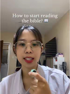 A woman with glasses holds a small object and speaks towards the camera, with text overlay at the top.