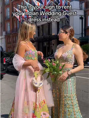 Two women stand in front of a building with flags, each wearing a colorful Indian wedding guest dress. Text overlays the top.