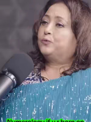 A woman with brown hair and a blue shawl is speaking into a microphone. The background is a plain, textured gray. Text is overlaid at the bottom of the image in green.