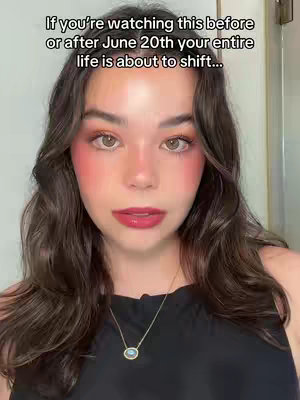 A close-up shot of a young woman with long, dark hair and rosy cheeks. She is wearing a black top and a delicate necklace. The image has a soft, warm lighting and focus is given on her face. Text overlayed at the top claims that if the viewer is watching the video before or after June 20th, their entire life is about to shift.