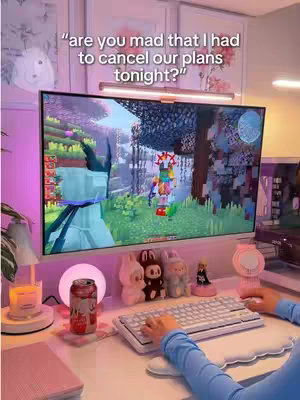 A person playing a game on a computer with a pink setup, with a monitor showing a Minecraft game. A text overlay is over the image.