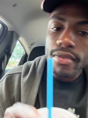 The cover image displays a close-up of a dark-skinned male in a car, holding a blue straw. He's wearing a dark gray hoodie and a red and black baseball cap. The interior of the car and outside view are visible in the background. The man's expression is neutral, suggesting a casual, everyday moment.