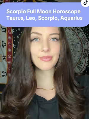 A woman with long brown hair and fair skin smiles at the camera. She wears a simple black top and a thin gold necklace. Behind her, a tapestry with a spiritual design is visible. A light blue rectangle above her head contains white text.