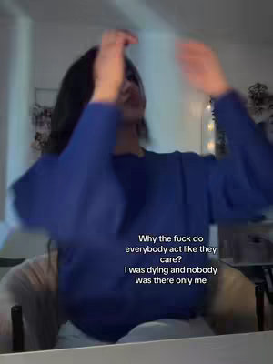 A person in a blue top appears to be in distress, with arms raised as if in a moment of emotional upheaval. The background is slightly blurred, suggesting a domestic setting. Text overlays appear. The overall color palette is muted.