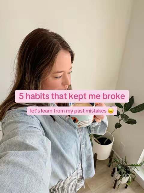 A woman is holding a mug, looking down at it. The image has a soft, natural lighting and a warm color palette. The composition is simple, with the main subject off-center. The background includes a plain wall, a window, and some plants, creating a casual, intimate setting.