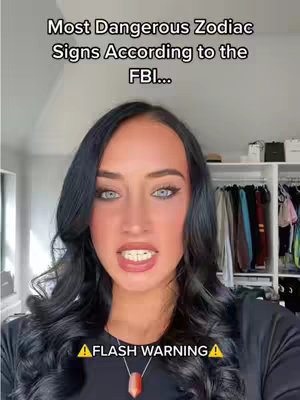 A woman with long, dark wavy hair and blue eyes looks directly at the camera, her mouth slightly open. Above her is text stating 'Most Dangerous Zodiac Signs According to the FBI...'. At the bottom, yellow text appears, 'FLASH WARNING'. The background shows a closet with clothes and shelves.