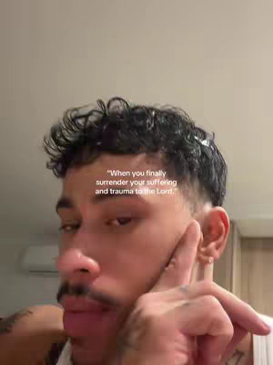 A close-up shot of a man with dark curly hair, a mustache, and a slight beard. He is touching his face with his right hand, and there is text overlaid on the image.