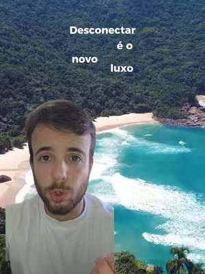 The cover image is a split composition featuring a person and a scenic view. On the left, a man looks directly at the camera with an open mouth. On the right, a tropical beach scene with turquoise water, white sand, and green vegetation fills the space. Above the man, white text layers read 'Desconectar, é o novo, luxo'. The color palette includes shades of green, blue, and skin tones.