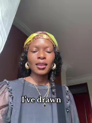 A woman with dark skin wearing a yellow headscarf and gold earrings looks at the camera. Text overlayed on the image reads "I've drawn". The background is blurred, with a partially visible window.